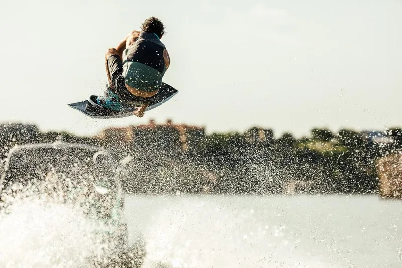 Slide: The Image of Wakeboarder performing a jump behind a 2023 Tigé 24RZX boat. - 17