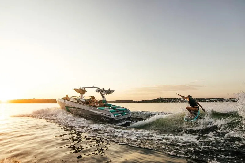 Slide: The Image of 2023 Tigé 24RZX boat with wakeboarder at sunset on a lake. - 2