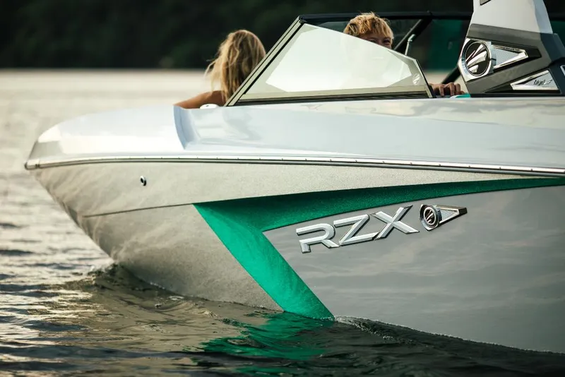 Slide: The Image of 2023 Tigé 24RZX boat cruising on water, close-up of side and logo. - 28