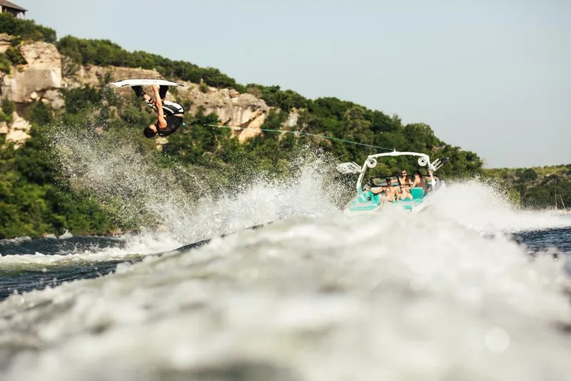 Slide: The Image of Wakeboarder performing a flip behind a 2023 Tigé 24RZX boat on a scenic lake. - 31
