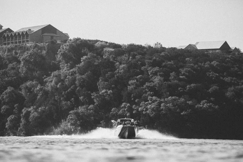 Slide: The Image of 2023 Tigé 24RZX boat cruising on a lake with forested hills in the background. - 32