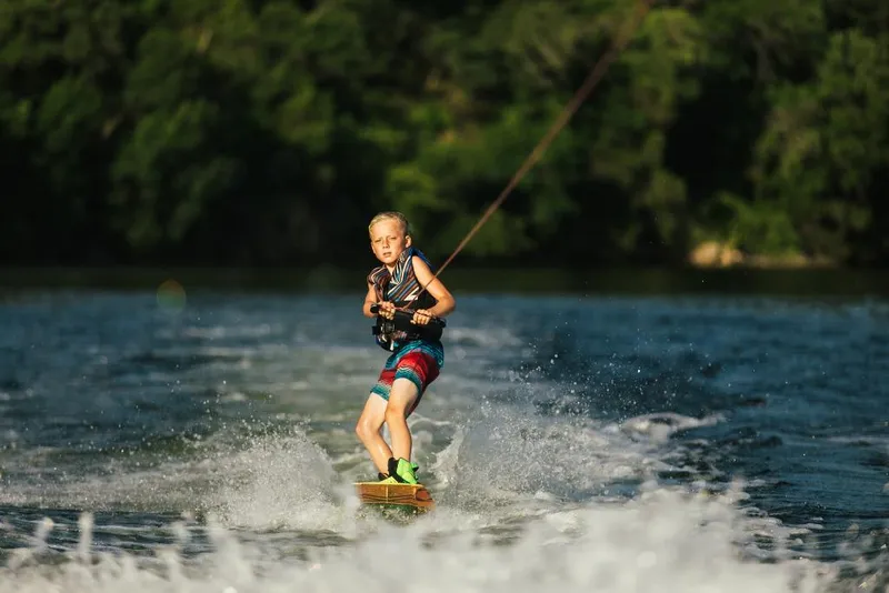 Slide: The Image of Young boy wakeboarding behind a 2023 Tigé 24RZX boat on a sunny day. - 35