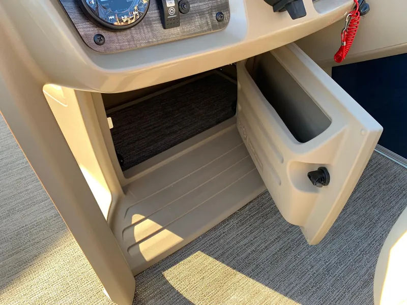 Slide: The Image of 2024 Starcraft LX22 R boat storage compartment with open door and dashboard. - 6