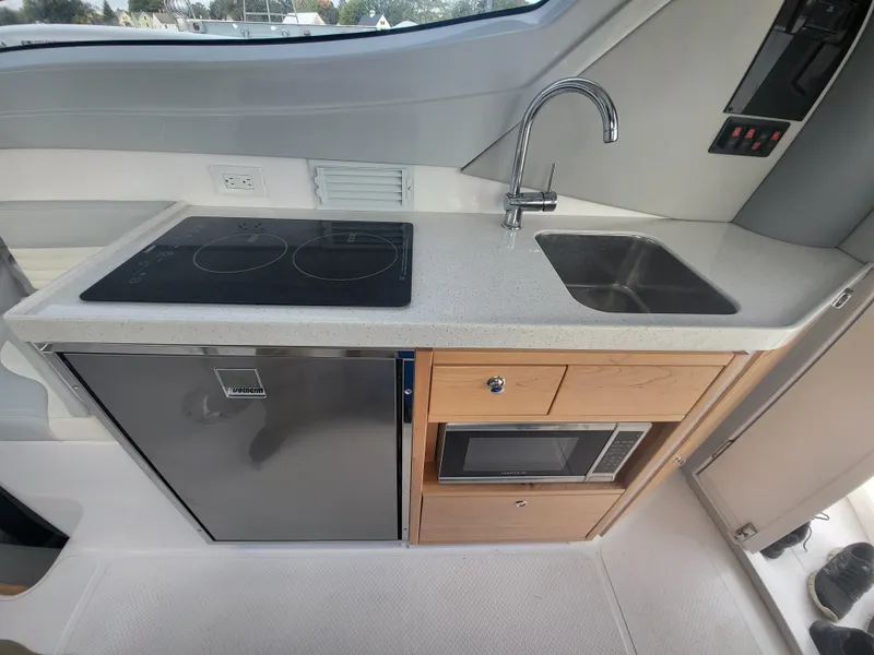 Slide: The Image of Modern kitchen area in 2024 ArrowCat 320 boat with stove, sink, fridge, and microwave. - 2