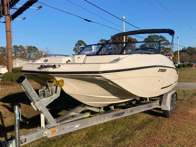 Slide: The Image of 2024 Starcraft SVX 210 boat on a trailer in a grassy area. - 2
