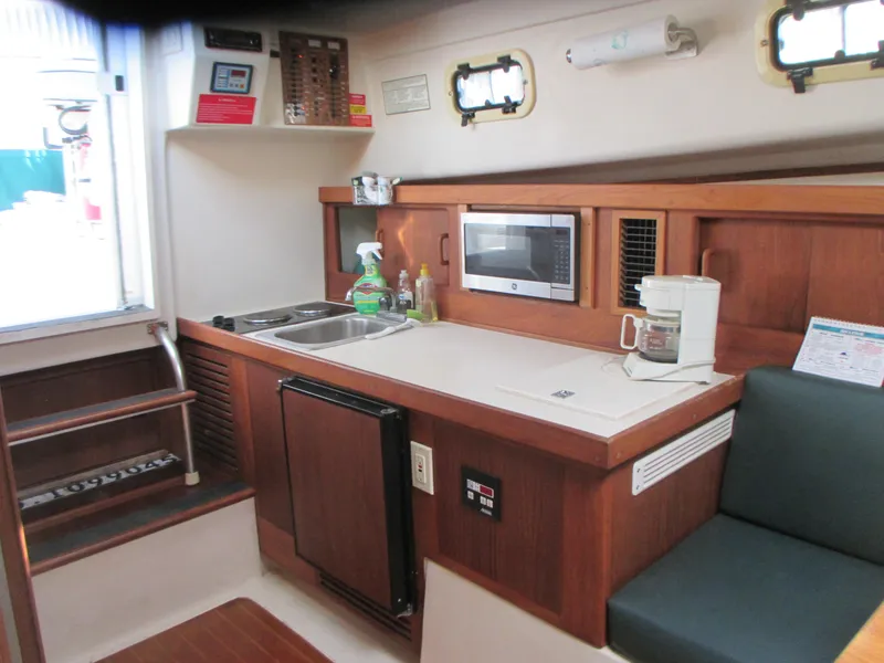 Slide: The Image of Mainship 30 PILOT 2000 boat interior with kitchenette, microwave, sink, and seating area. - 15