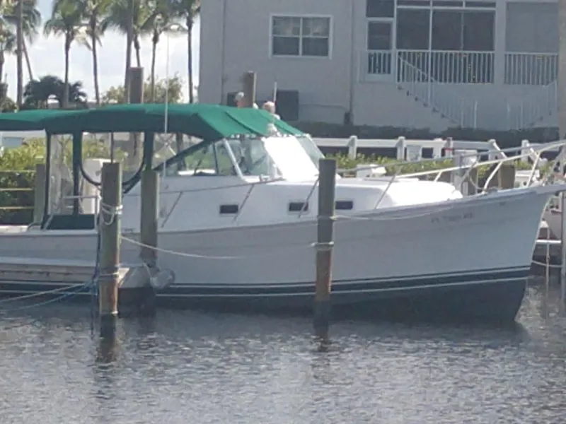 Slide: The Image of 2000 Mainship 30 PILOT boat docked with green canopy. - 2