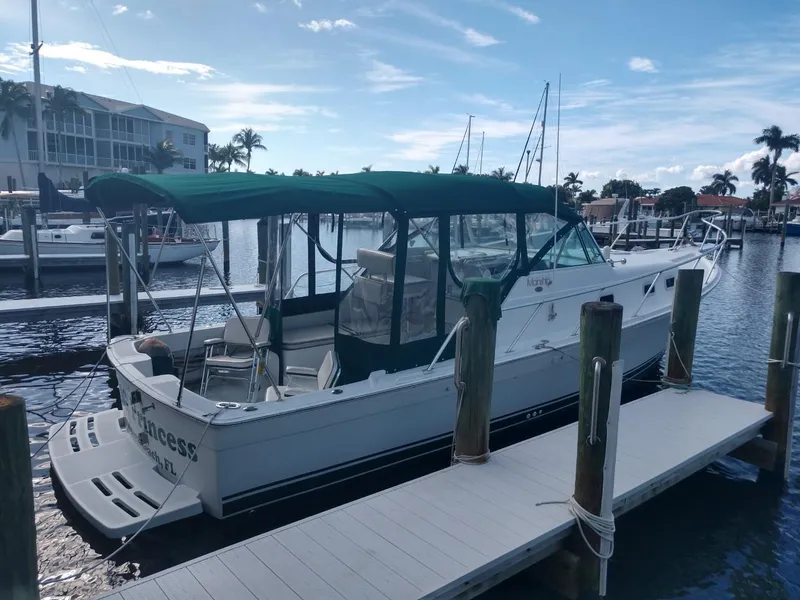 Slide: The Image of 2000 Mainship 30 PILOT boat docked at a marina with green canopy. - 4