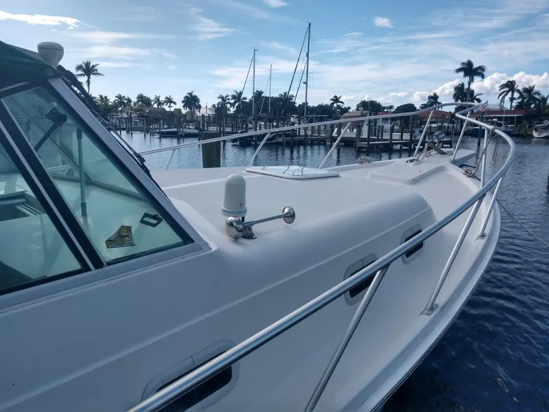 Slide: The Image of 2000 Mainship 30 PILOT boat docked at a marina with palm trees in the background. - 5