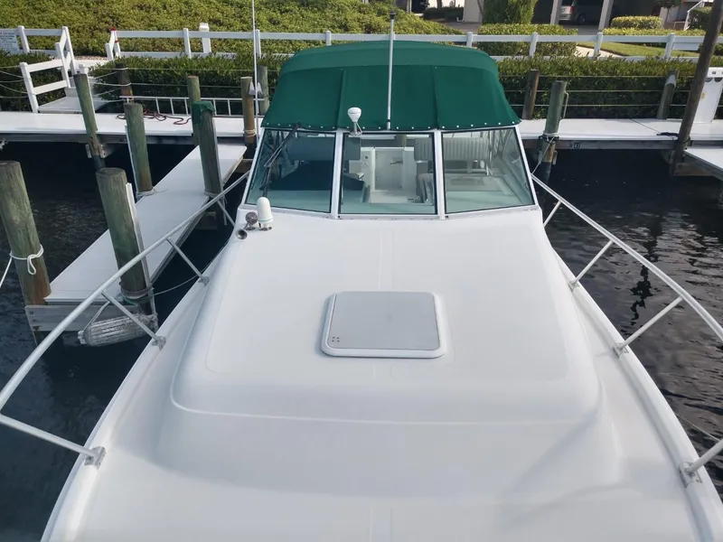 Slide: The Image of 2000 Mainship 30 PILOT boat docked, green canopy, white deck, marina background. - 6