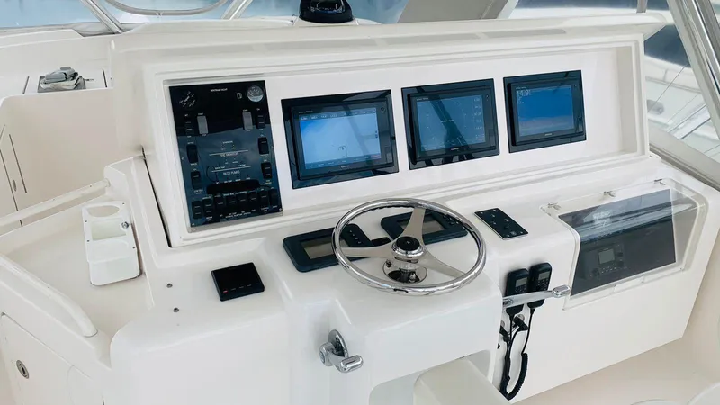 Slide: The Image of Control panel of a 2005 Bertram 570 yacht with multiple screens and steering wheel. - 4