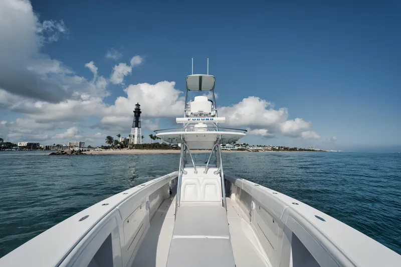 Slide: The Image of Jupiter 38 CC boat cruising near a lighthouse under a clear blue sky. - 13