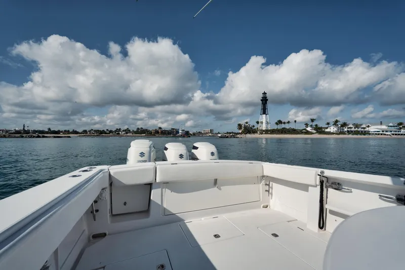 Slide: The Image of 2010 Jupiter 38 CC boat with triple engines, ocean view, and distant lighthouse under cloudy sky. - 19