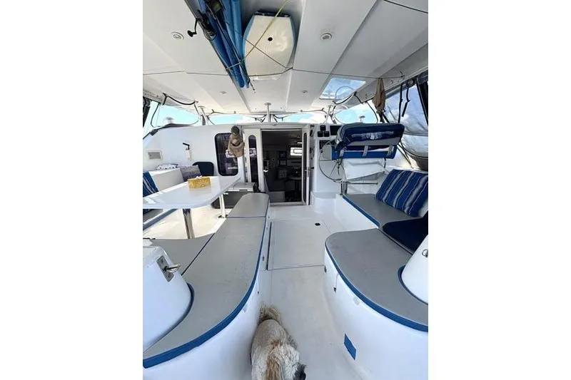 Slide: The Image of 1998 Leopard Catamaran interior with seating, table, and a dog on deck. - 12