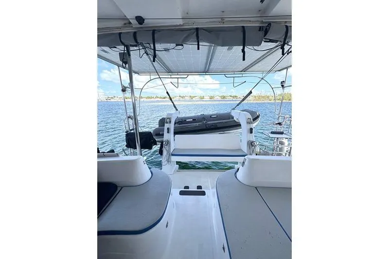 Slide: The Image of 1998 Leopard Catamaran deck view with seating, overlooking calm waters and a small boat. - 13