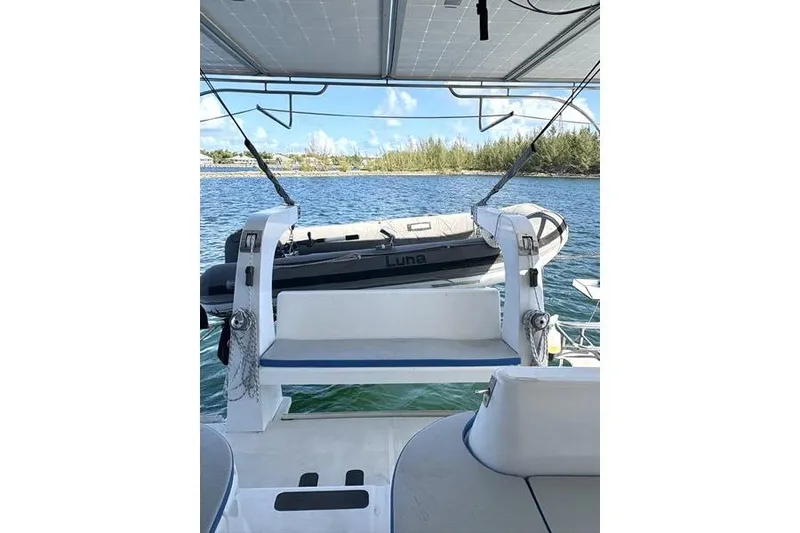 Slide: The Image of 1998 Leopard Catamaran with dinghy on deck, overlooking serene waters and distant shoreline. - 16