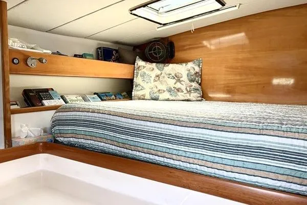 Slide: The Image of Cozy cabin interior of a 1998 Leopard Catamaran with striped bedding and wooden accents. - 20