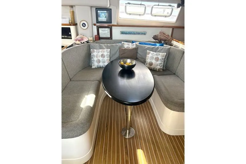 Slide: The Image of Interior of 1998 Leopard Catamaran with cozy seating, oval table, and decorative pillows. - 26