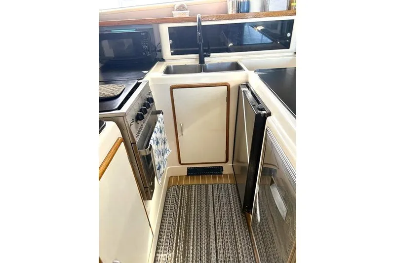 Slide: The Image of Compact kitchen in a 1998 Leopard Catamaran, featuring a sink, stove, and microwave. - 27