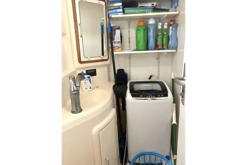Slide: The Image of Laundry area on a 1998 Leopard Catamaran with washing machine and cleaning supplies. - 28