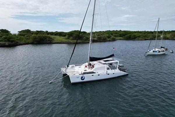 Slide: The Image of 1998 Leopard Catamaran anchored in serene waters near lush green shoreline. - 3