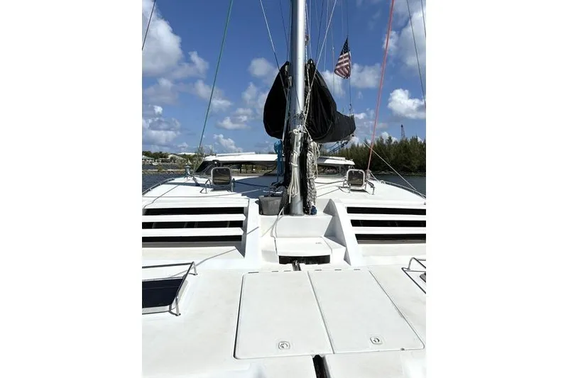 Slide: The Image of 1998 Leopard Catamaran deck with mast, sails, and American flag under blue sky. - 38