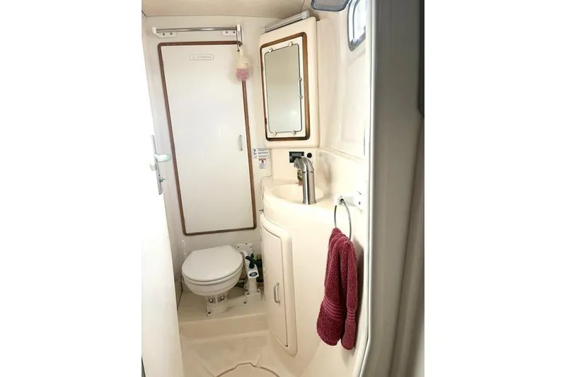 Slide: The Image of 1998 Leopard Catamaran bathroom with sink, mirror, toilet, and red towel. - 44