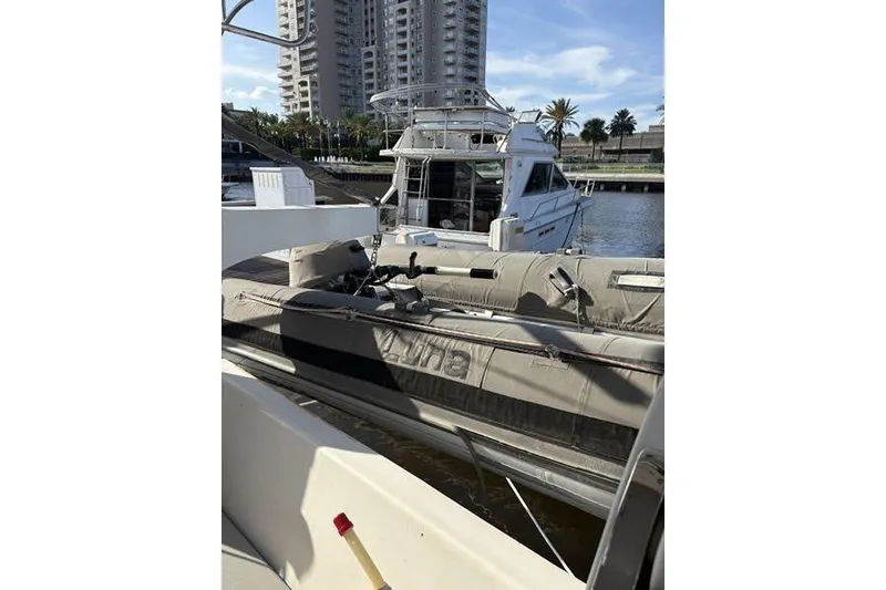 Slide: The Image of 1998 Leopard Catamaran docked near inflatable boat, with cityscape in background. - 50