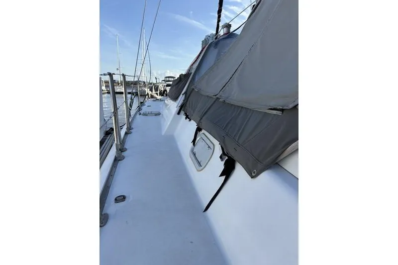 Slide: The Image of 1998 Leopard Catamaran deck view with covered sails in marina setting. - 52