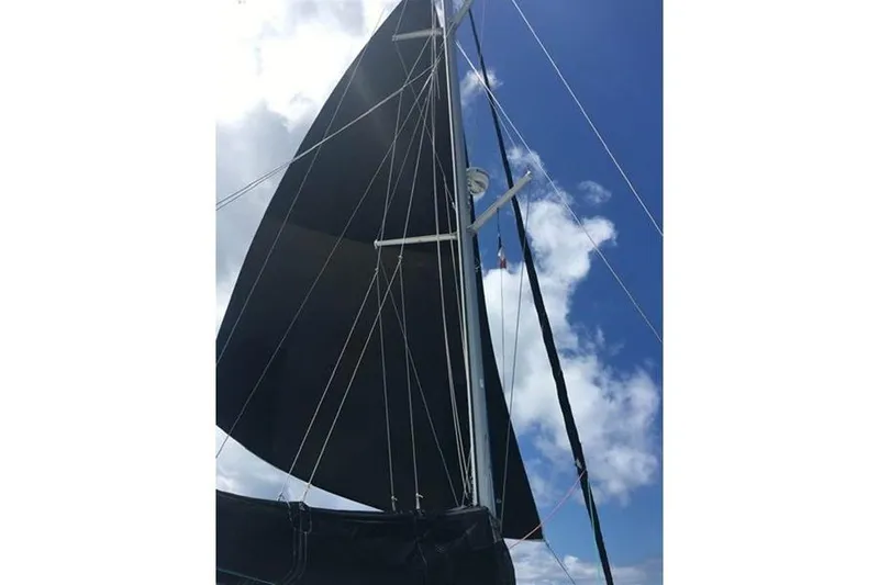 Slide: The Image of 1998 Leopard Catamaran with black sails against a blue sky. - 8