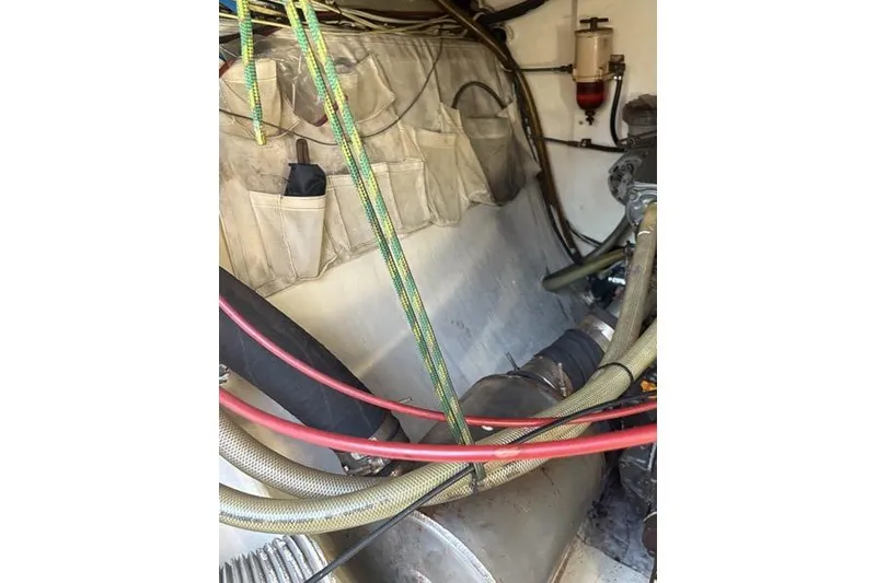 Slide: The Image of Engine room of a 1998 Leopard Catamaran with visible hoses and storage pockets. - 86