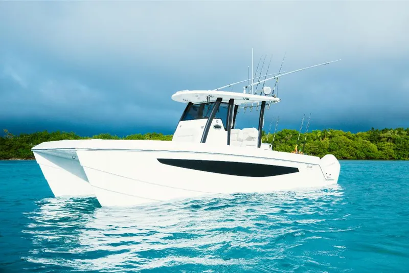 Slide: The Image of 2023 Aquila 28 Molokai boat on turquoise water with lush green background. - 0