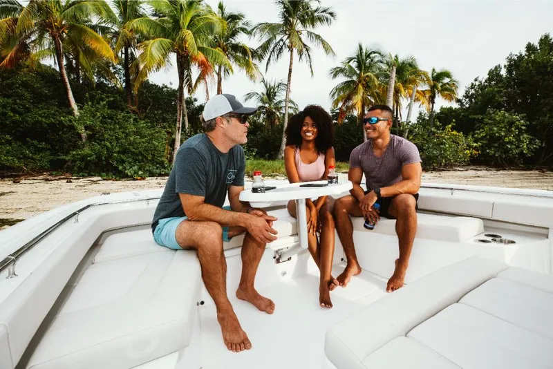 Slide: The Image of Three people relaxing on a 2023 Aquila 28 Molokai boat near a tropical beach. - 14
