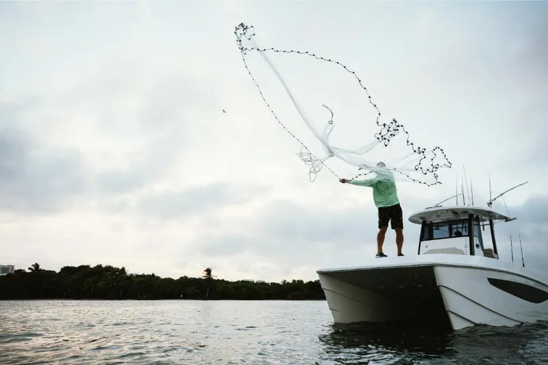 Slide: The Image of Person casting net from 2023 Aquila 28 Molokai boat on calm water. - 17