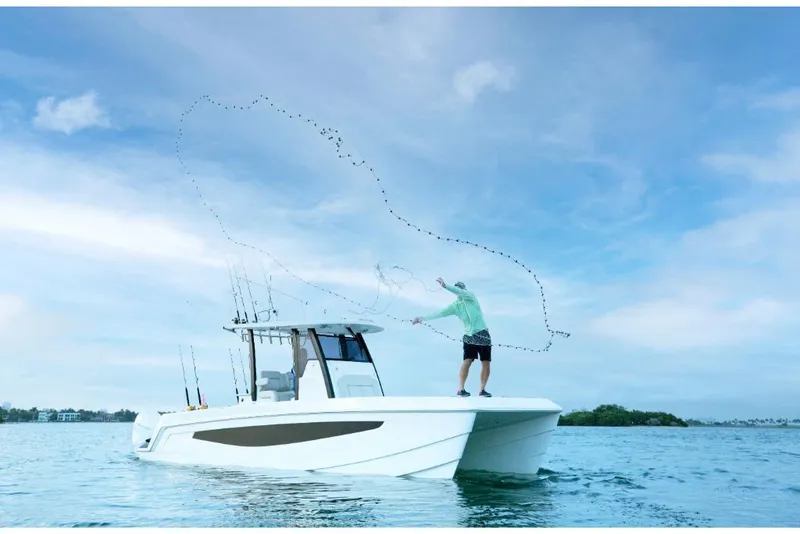 Slide: The Image of 2023 Aquila 28 Molokai boat with person casting fishing net on water. - 2