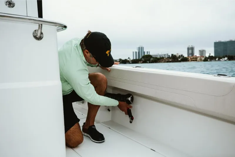 Slide: The Image of Man adjusting equipment on 2023 Aquila 28 Molokai boat near city waterfront. - 21