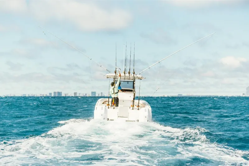 Slide: The Image of 2023 Aquila 28 Molokai boat cruising on open water with city skyline in background. - 4