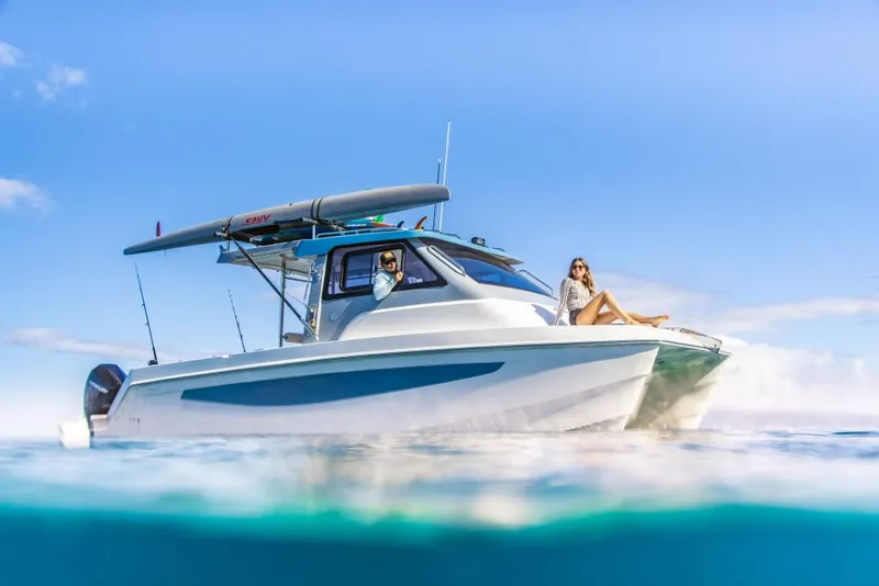 Slide: The Image of 2023 Aquila 28 Molokai Cuddy boat on clear blue water with people relaxing. - 11