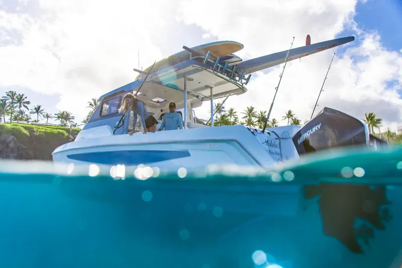 Slide: The Image of 2023 Aquila 28 Molokai Cuddy boat on clear blue water with people onboard. - 12