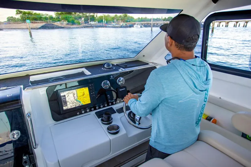 Slide: The Image of Man piloting 2023 Aquila 28 Molokai Cuddy boat with navigation system. - 15