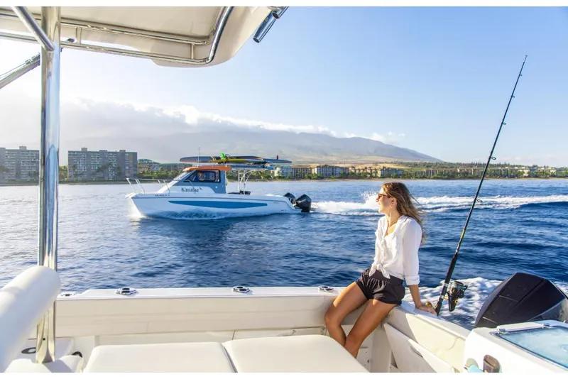 Slide: The Image of 2023 Aquila 28 Molokai Cuddy boat on water with woman relaxing onboard. - 20