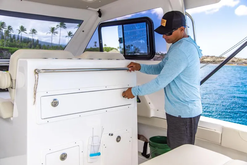 Slide: The Image of Man on 2023 Aquila 28 Molokai Cuddy boat adjusting storage compartment. - 25