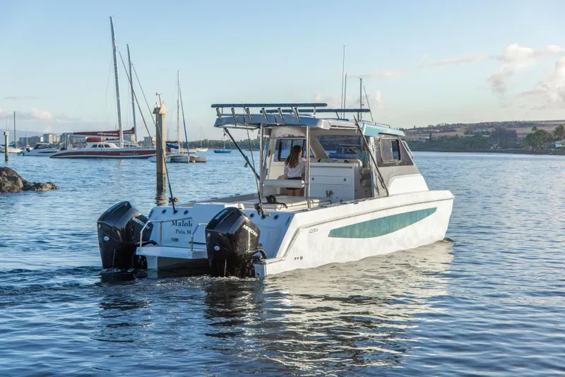 Slide: The Image of 2023 Aquila 28 Molokai Cuddy boat on calm water with other boats in the background. - 3