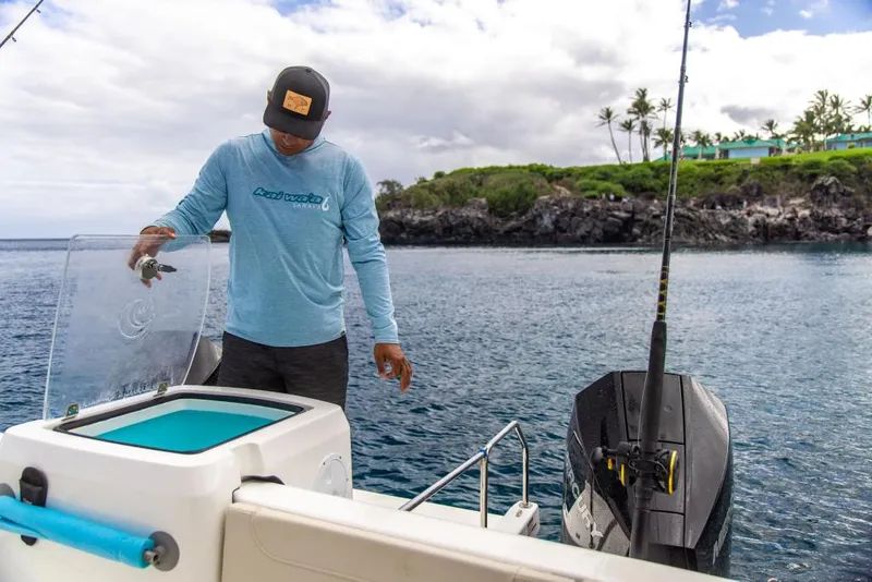 Slide: The Image of Man fishing on 2023 Aquila 28 Molokai Cuddy boat near rocky shoreline. - 30