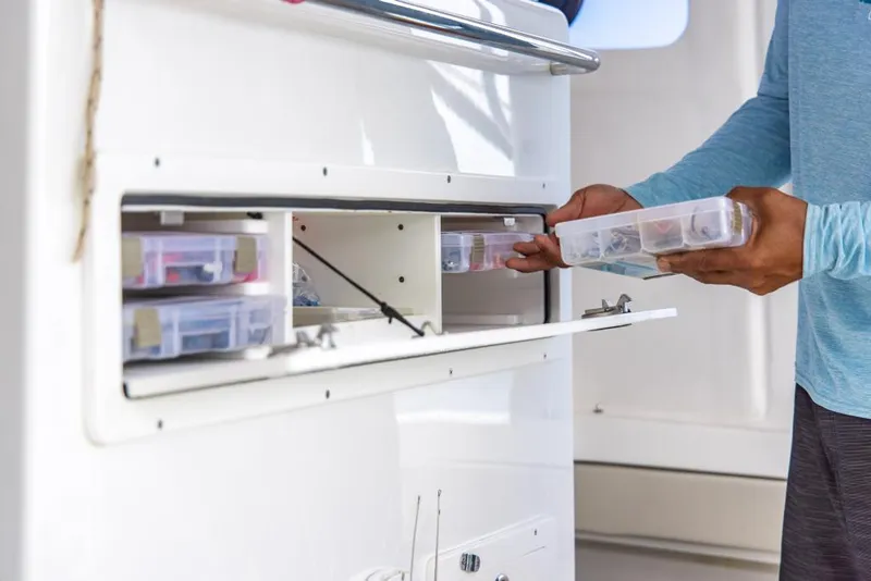 Slide: The Image of Man organizing tackle boxes on 2023 Aquila 28 Molokai Cuddy boat. - 31