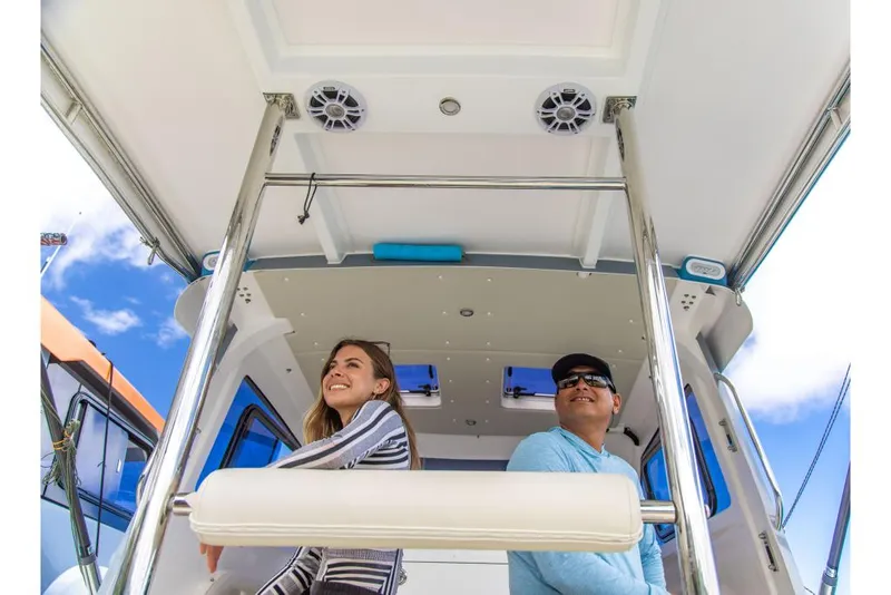 Slide: The Image of 2023 Aquila 28 Molokai Cuddy boat interior with two people enjoying the ride. - 32