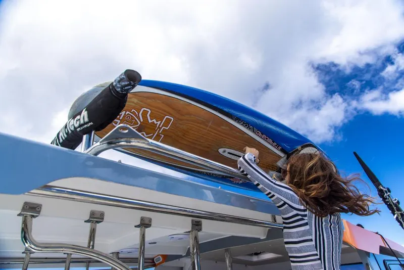 Slide: The Image of Woman securing surfboard on 2023 Aquila 28 Molokai Cuddy boat. - 37
