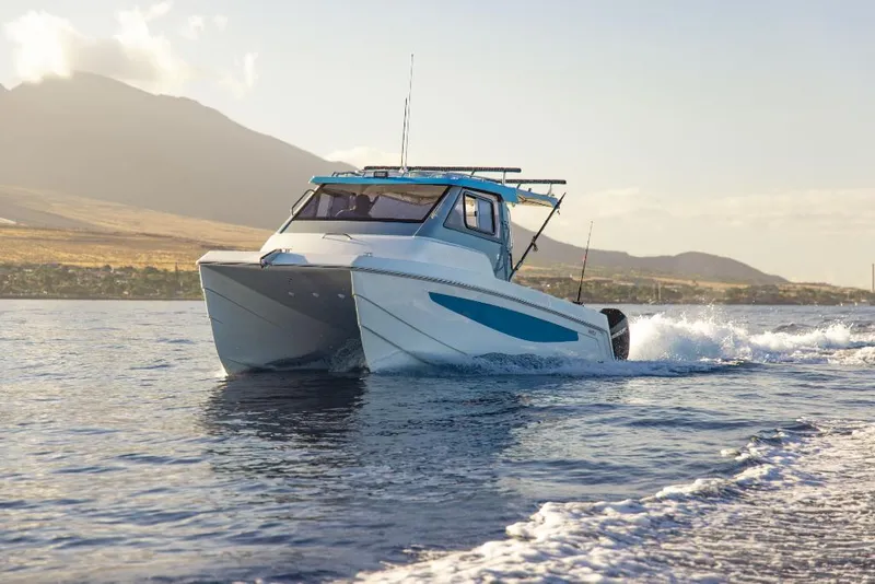 Slide: The Image of 2023 Aquila 28 Molokai Cuddy cruising on open water with scenic mountain backdrop. - 6