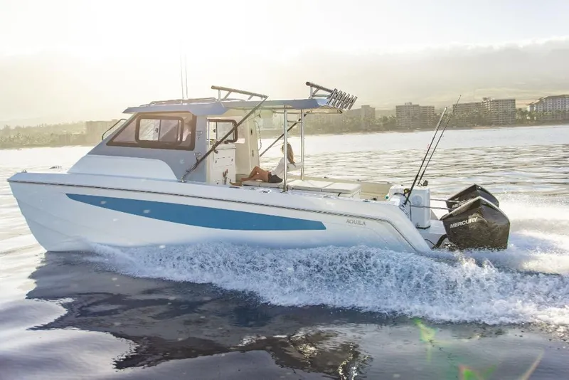 Slide: The Image of 2023 Aquila 28 Molokai Cuddy cruising on water with twin outboard engines. - 7