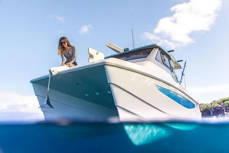 Slide: The Image of 2023 Aquila 28 Molokai Cuddy boat on water with a person on deck. - 9